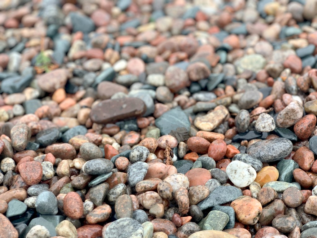A close up of various colourful wet rocks on a beach
